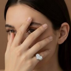 A handcrafted 925 sterling silver chevalier ring with a sculptural heart shape and raw texture, displayed on elegant dark green silk fabric