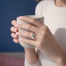 Woman’s hands holding a ceramic mug wearing a handmade sculptural sterling silver ring in natural sunlight